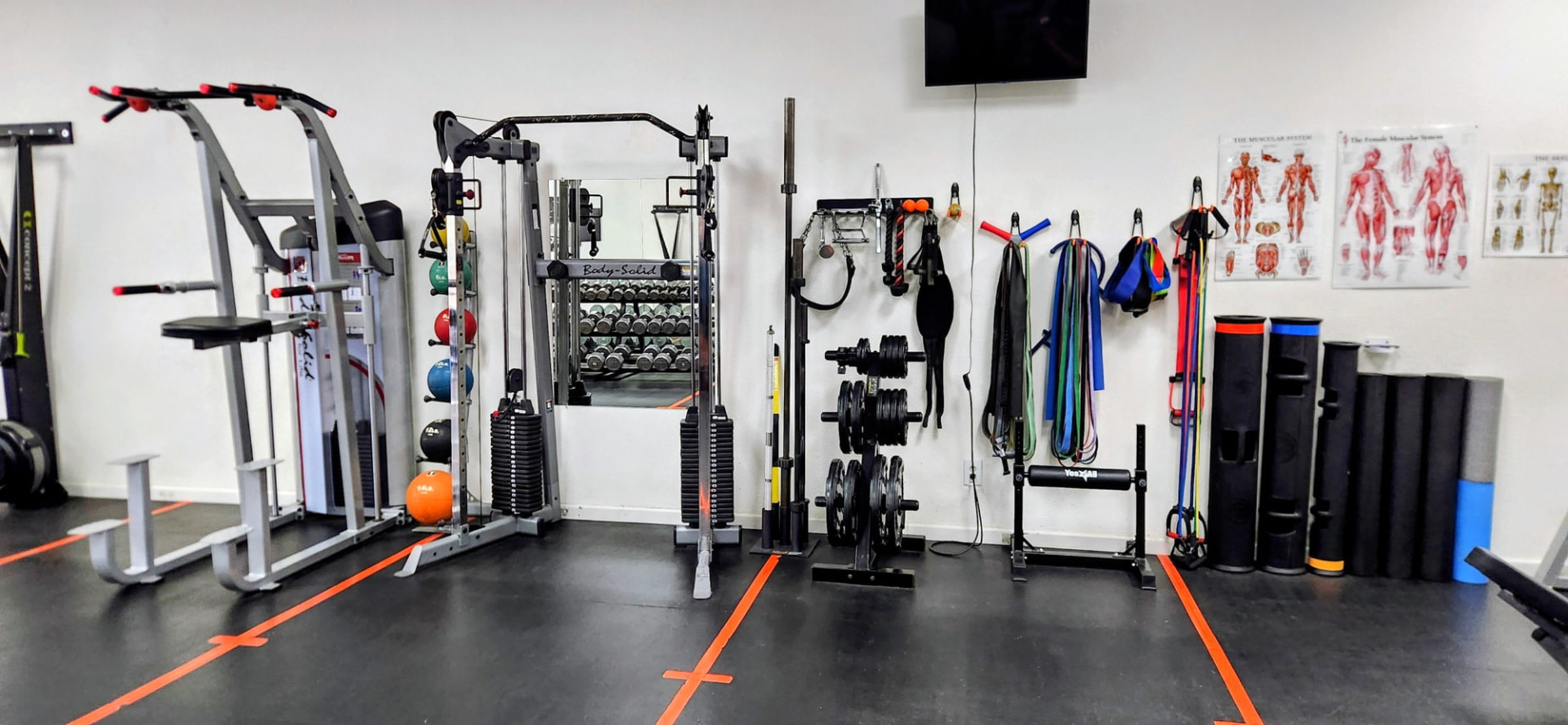 Functional trainer, bands, plates and foam rollers along the studio wall