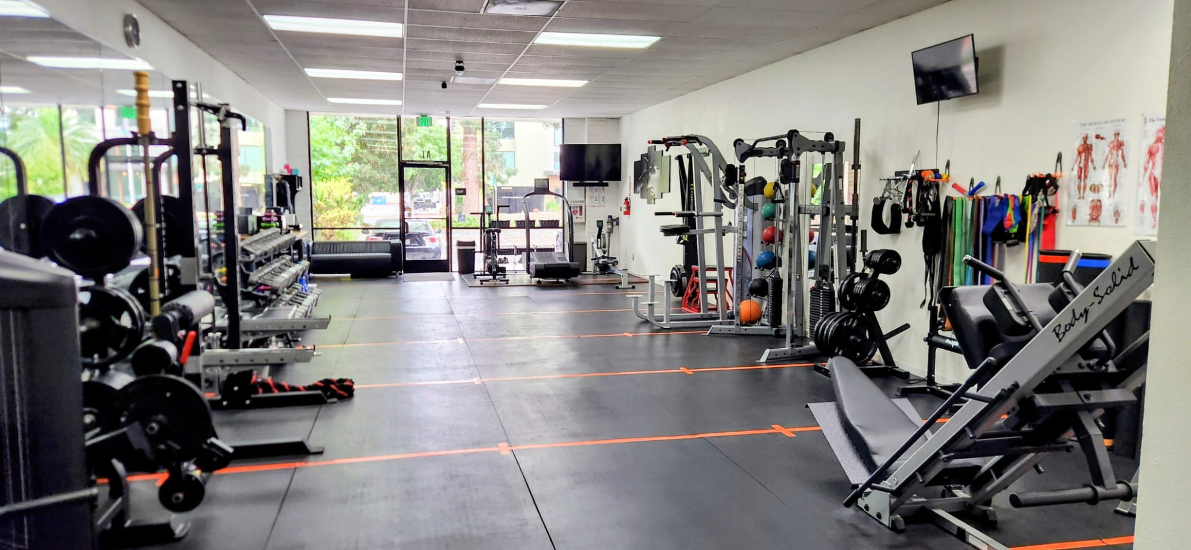 Leg press, racks and dumbbells along the length of the Helios Fit studio